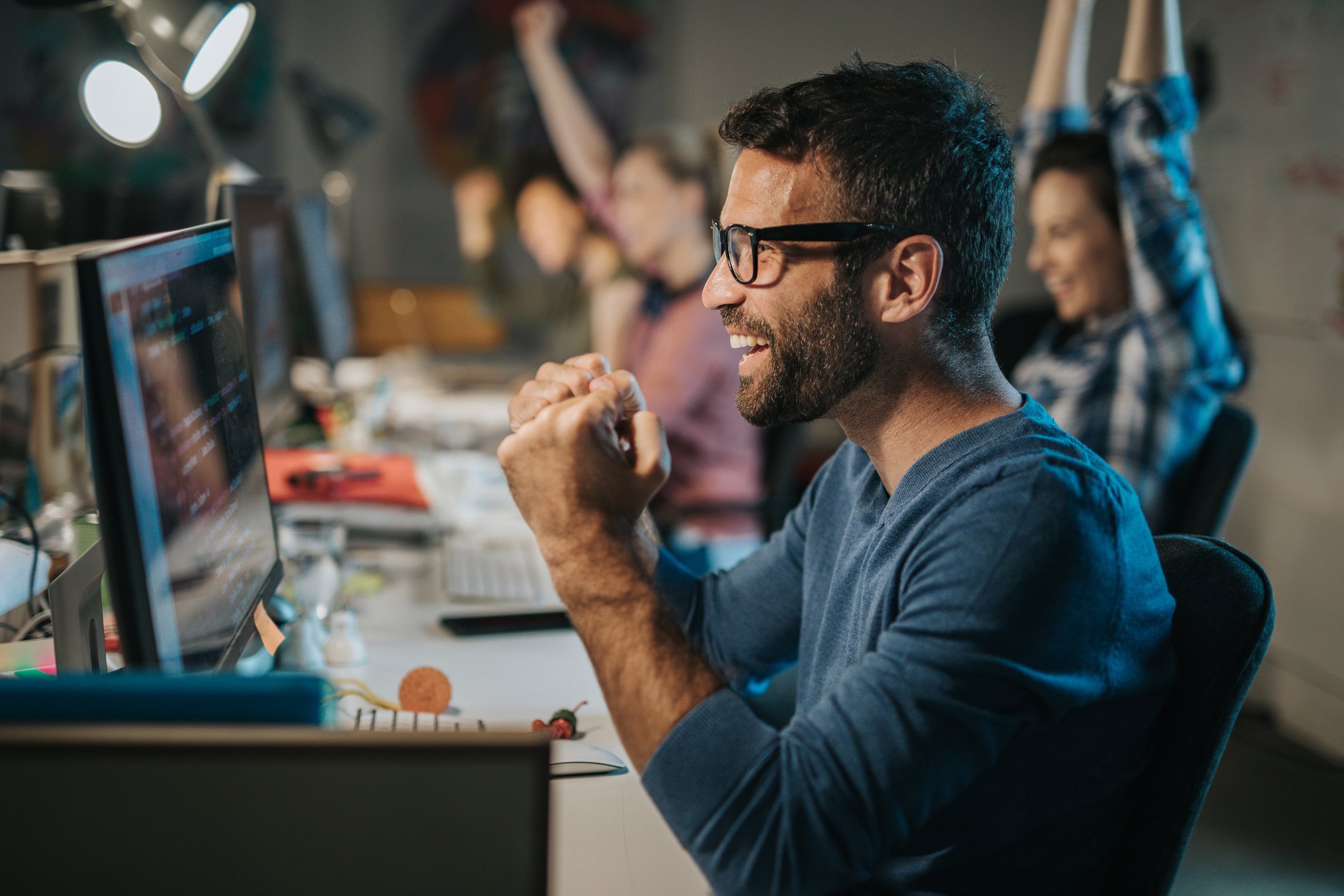 Cheerful computer programmer celebrating success in the office.